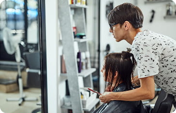 美容室で美容師が女性客の髪をカットしている施術シーン