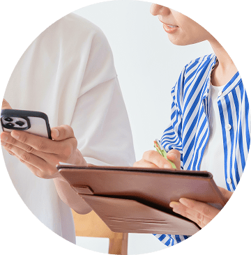 スマートフォンを持つ人物と、タブレットにメモを取る人物の手元の様子