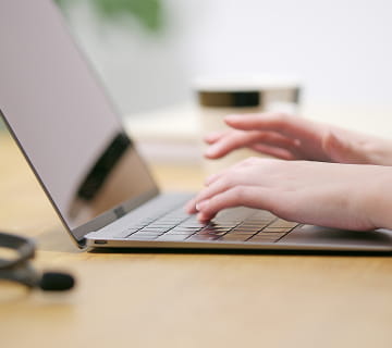 ノートパソコンのキーボードをタイピングする手元の様子